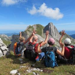Vier Wandersleut‘ sitzen im Gras und winken dem Gipfel des Altmann zu.